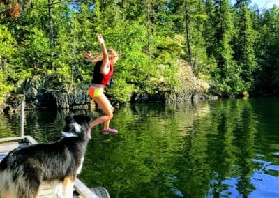 Girl jumping off main lodge dock into the clear Manitou waters for a swim