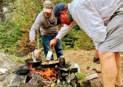 Fishing Guides cooking fresh fish over shore lunch camp fire