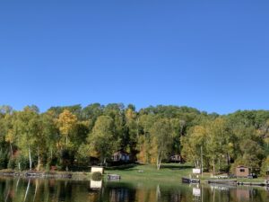 Cabins along Barker Bay lakeshore at Manitou Weather Station with autumn trees and clear blue sky in Northwestern Ontario.