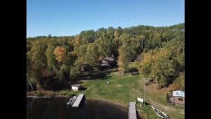 Drone photo of Barker Bay showing cabins surrounded by autumn trees, docks, and green lawn at Manitou Weather Station Ontario.